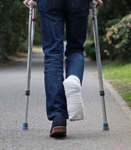 person walking on crutches in park away from camera | Boulder Personal Injury Lawyer