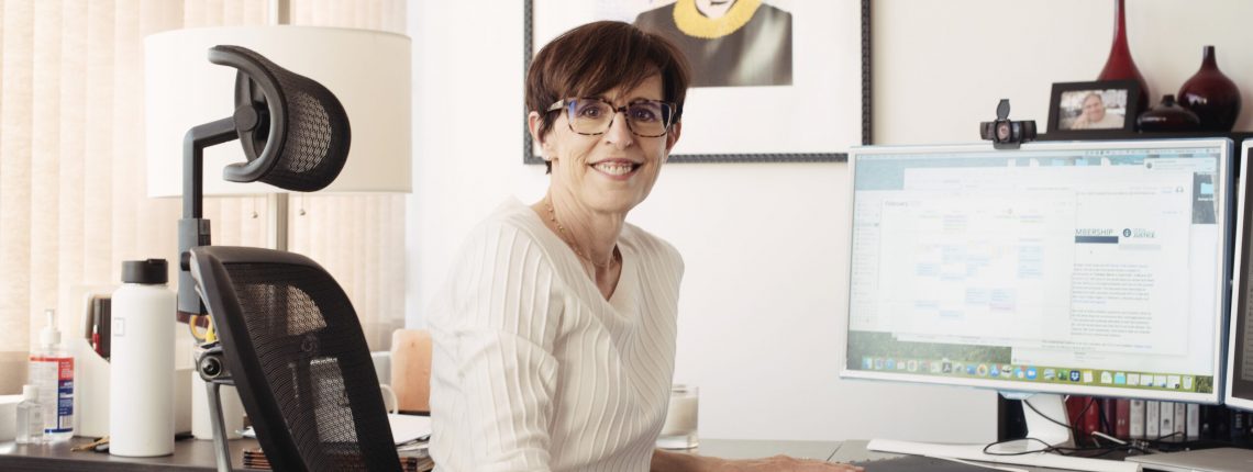 Debbie at her desk wearing a white sweater