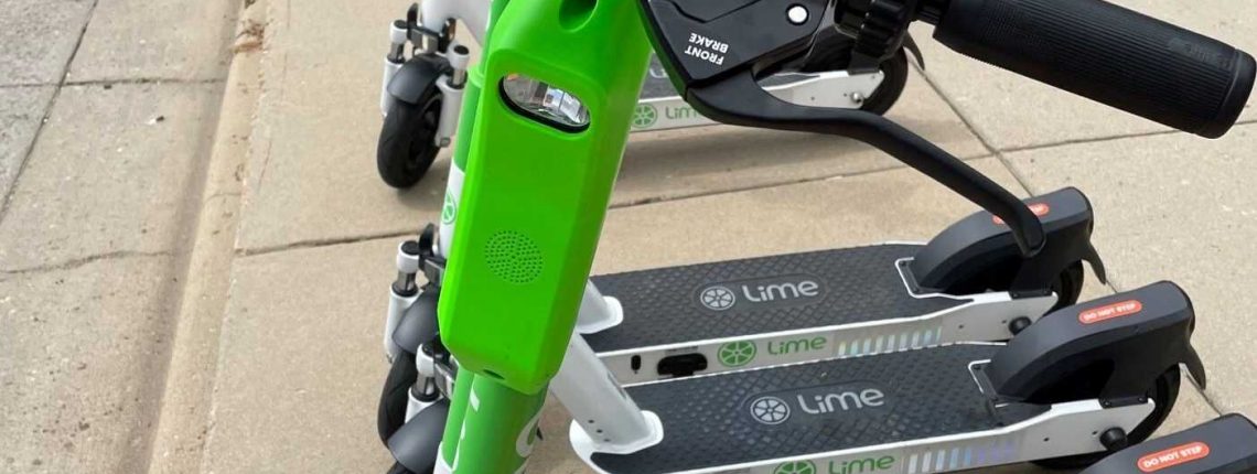 Lime e-scooters lined up on sidewalk