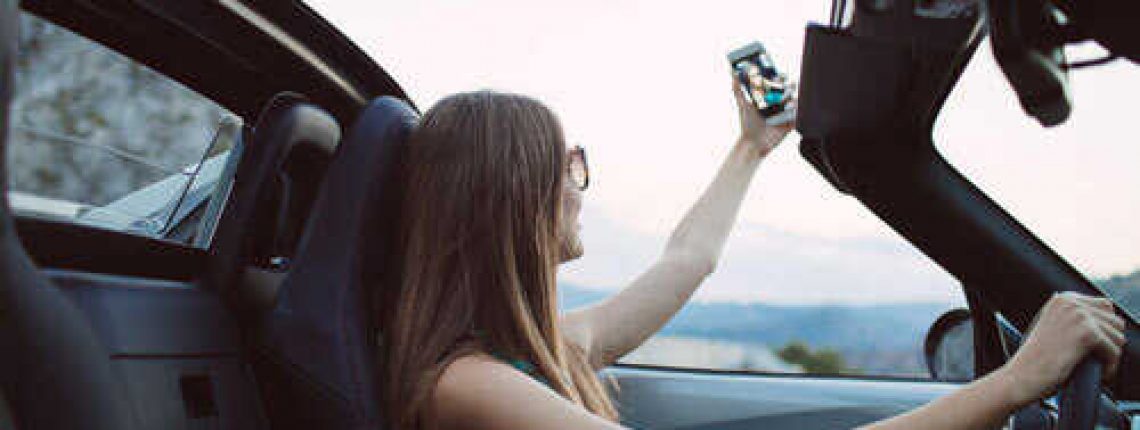 Young-female-taking-selfie-in-convertible-car-sm